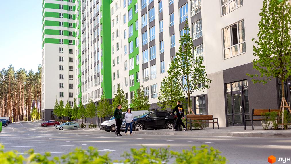 Житловий комплекс City Park з біло-зеленими фасадами та рядами вікон. Навколо новобудови облаштовано паркінг та висаджено дерева.