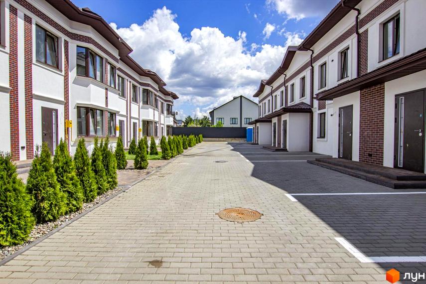 Таунхауси на Львівському: фасади будинків з цегляними елементами та акуратна прибудинкова територія з туями та бруківкою.