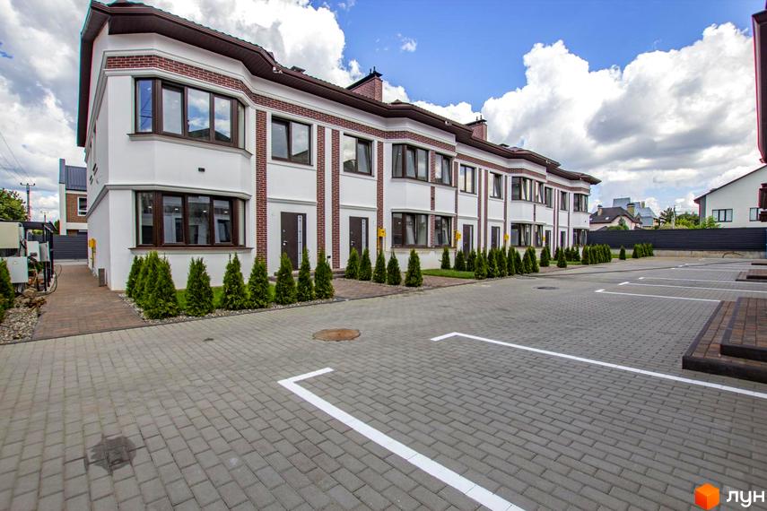 Таунхауси на Львівському: фасади біло-цегляних будинків з коричневими вікнами та прибудинкова територія з парковкою.