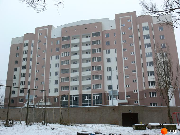 Будинок житлового комплексу Супутник з фасадом у світлих тонах. Прибудинкова територія з огорожею та зеленими насадженнями.