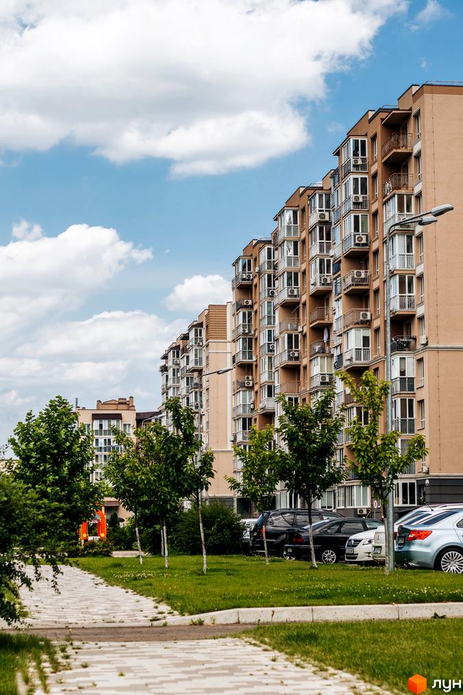 Житловий комплекс Кришталеві джерела з сучасними балконами та зеленими насадженнями на прибудинковій території.