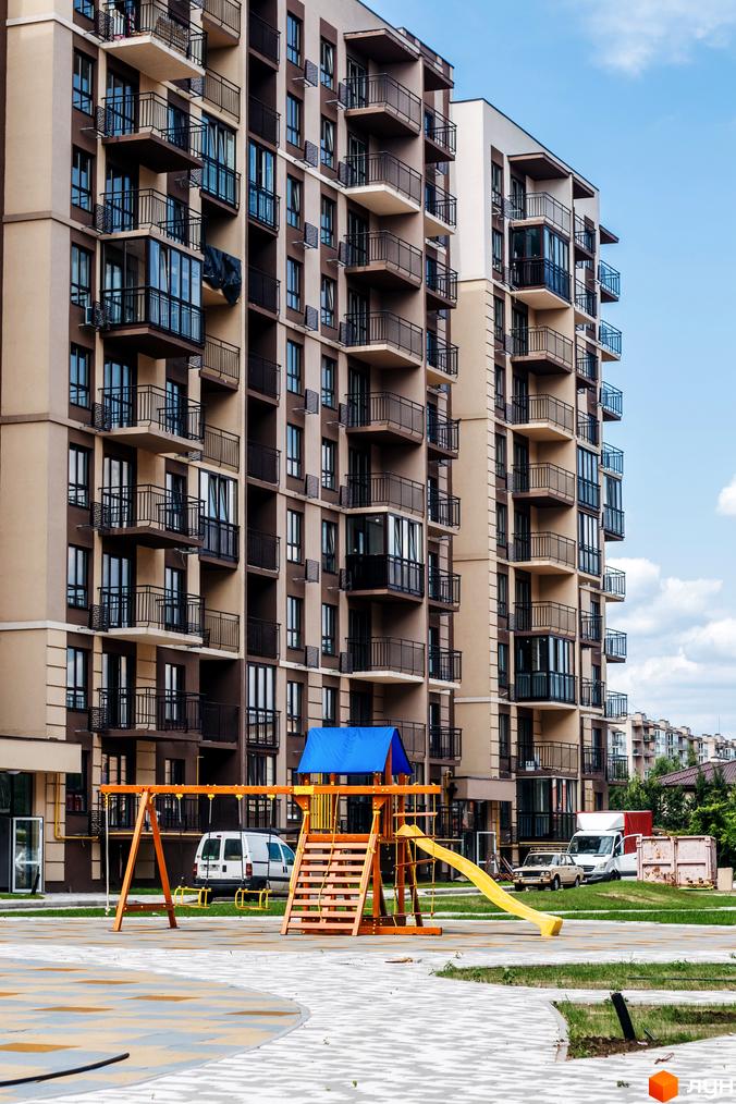 Житловий комплекс Кришталеві джерела з балконами, прибудинкова територія з дитячим майданчиком.