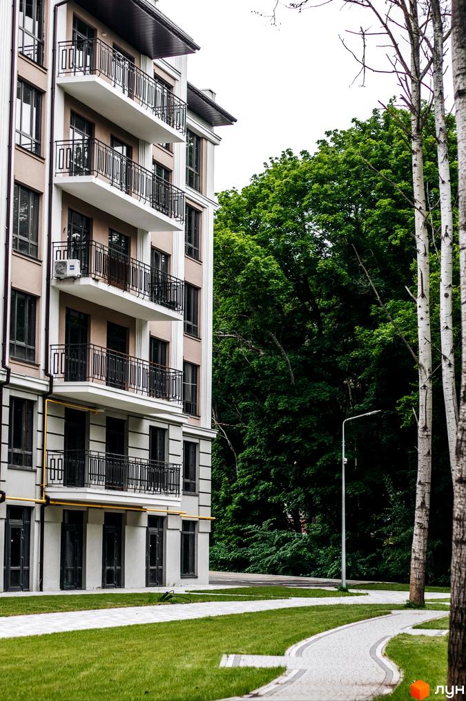 Фасад житлового комплексу Кришталеві джерела з балконами та вікнами. Прибудинкова територія з доріжками та зеленню.