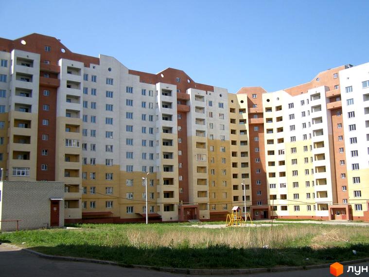 Житловий комплекс на вул. Героїв Праці, 32г, з фасадом у світлих відтінках. Прибудинкова територія з дитячим майданчиком та зеленими насадженнями.