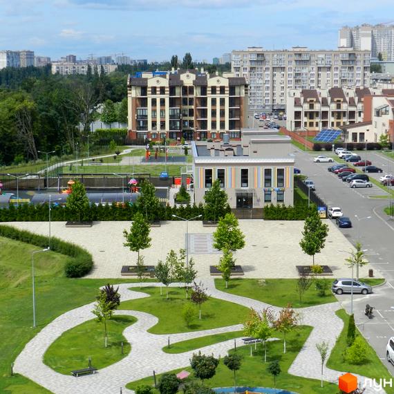 Житловий комплекс Кришталеві джерела. Фасад багатоповерхового будинку з коричневими елементами, прибудинкова територія з зеленими насадженнями та дитячим майданчиком.