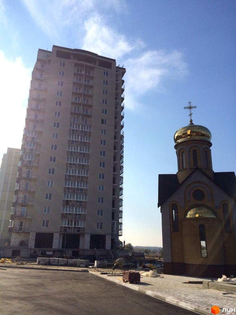 Житловий комплекс ЖБ Маяк з висотним будинком та невеликою церквою на прибудинковій території.