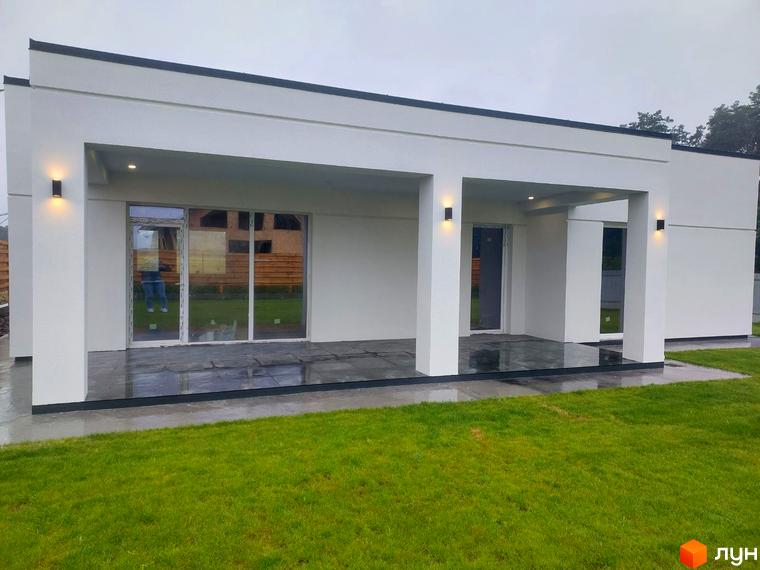 Котеджне містечко КМ Лісне: одноповерховий будинок з білою фасадною штукатуркою, панорамними вікнами та критою терасою. Прибудинкова територія з доглянутим газоном.