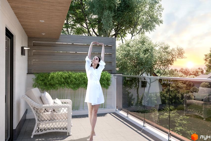 Таунхауси Lisopark. Дівчина в білому халаті робить зарядку на терасі з видом на зелені дерева та захід сонця.