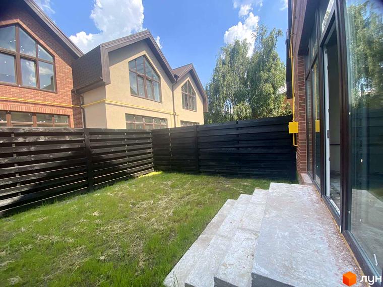 Зображення таунхаусів Modern House з фасадами з цегли та світлої штукатурки, облаштована прибудинкова територія з газоном та парканом.