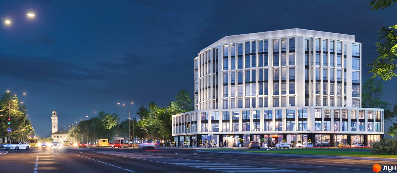Житловий комплекс Standard LUX у вечірній час, з фасадом з великою кількістю вікон та комерційними приміщеннями на першому поверсі. Навколо будівлі розташовані дерева та вулиця з автомобілями.