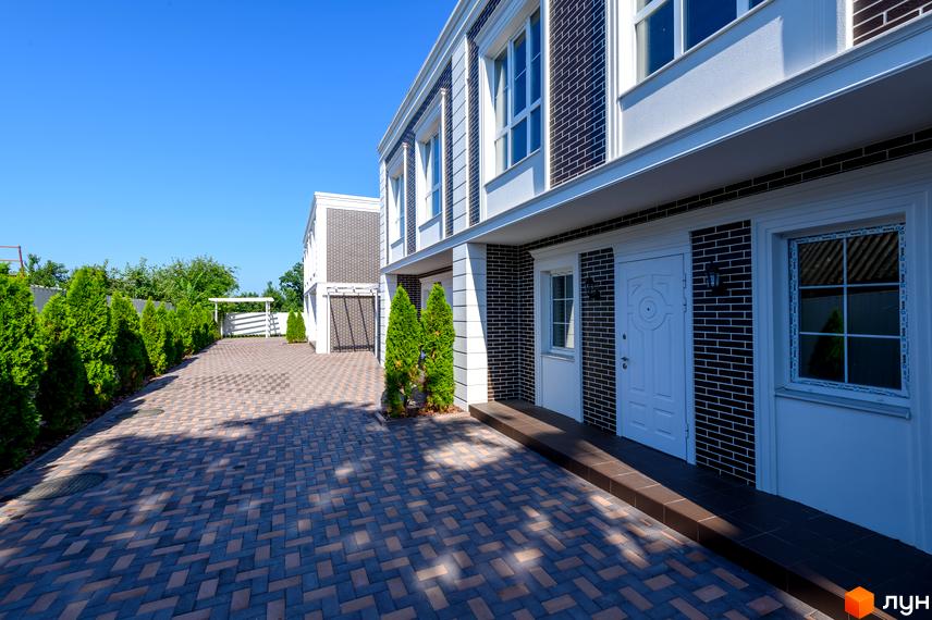 Feofaniya Home - сучасний житловий комплекс з цегляним фасадом та брукованою прибудинковою територією. Зелені туї вздовж доріжки створюють затишну атмосферу.