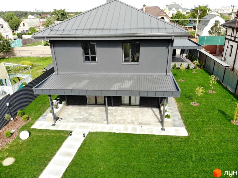 Котеджне містечко Kulbaba Petropavlivka: двоповерховий будинок сірого кольору з металевим дахом. Навколо доглянутий зелений газон та вимощена тераса.