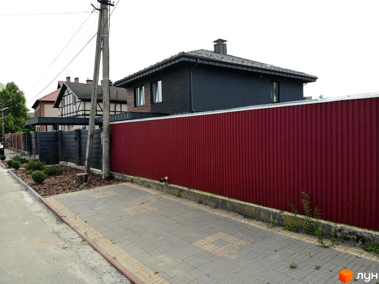 КМ Kulbaba Petropavlivka: будинок з темним фасадом, червоний паркан, бруківка та зелені насадження.