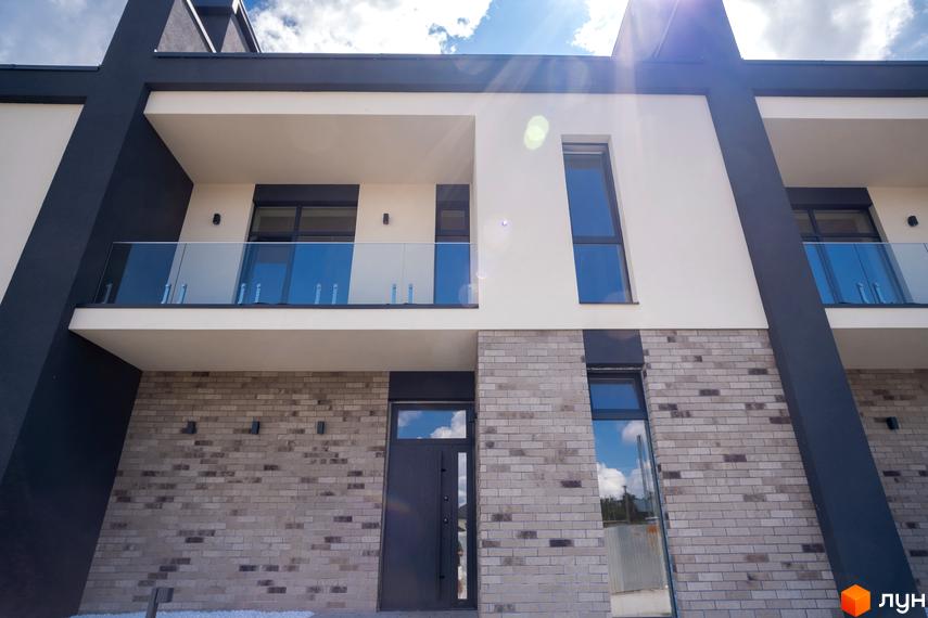 Фасад будинку Котеджного містечка Квадрат TOWN з світлими стінами, світло-сірою цеглою та темними акцентами. Наявні балкони зі скляними огорожами.