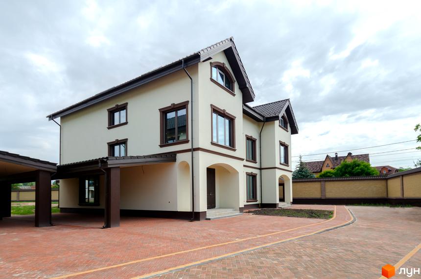 Котеджне містечко КМ Vita Energy residence з світлими фасадами та темними віконними рамами, розташоване на брукованій прибудинковій території.