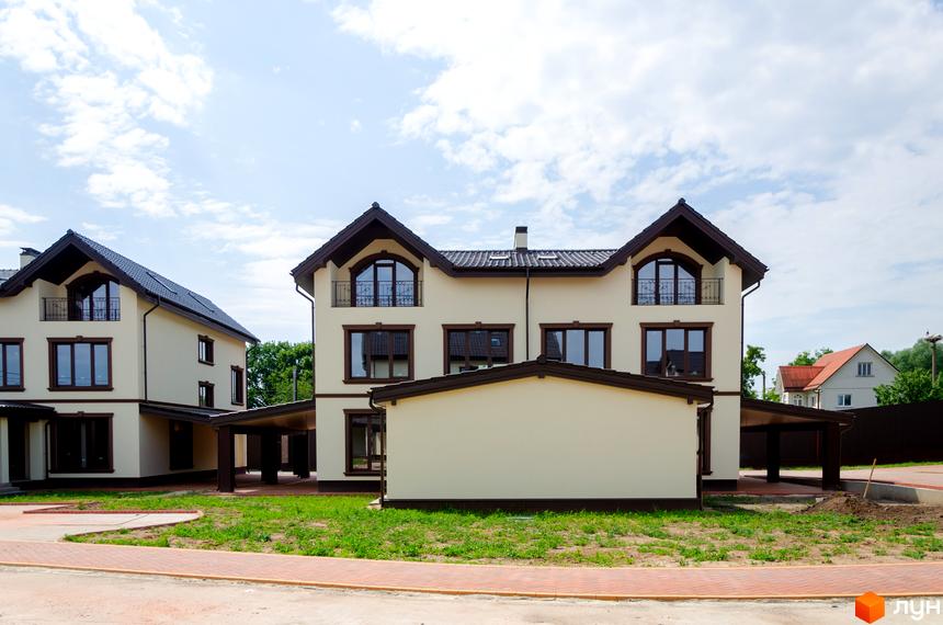 Котеджне містечко КМ Vita Energy residence: двоповерхові будинки світло-бежевого кольору з темними дахами та вікнами, зелена прибудинкова територія з доріжками.
