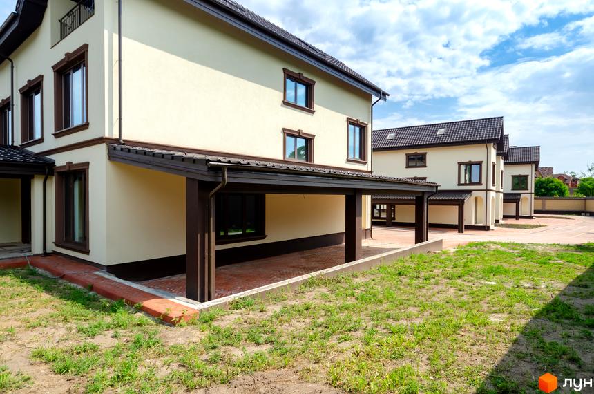 Котеджне містечко КМ Vita Energy residence: двоповерхові будинки світло-бежевого кольору з коричневими віконними рамами та навісами. Прибудинкова територія з газоном та вимощеною доріжкою.