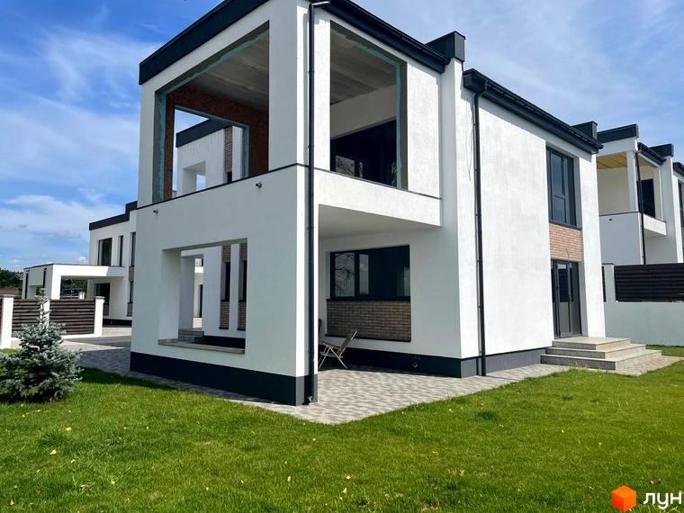 Котеджне містечко КМ Перлина Процева: білі двоповерхові будинки з чорними дахами, цегляними вставками та великими вікнами. Навколо зелений газон та бруківка.