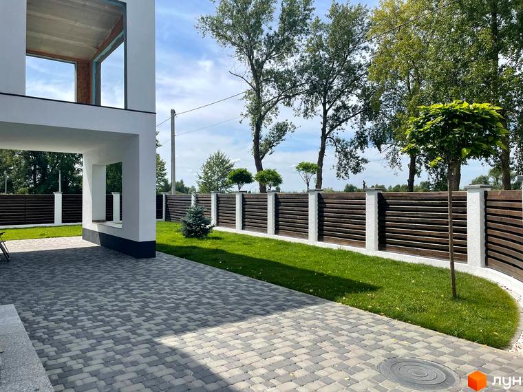 Котеджне містечко КМ Перлина Процева. Зовнішній вигляд будинку та облаштована прибудинкова територія з бруківкою та парканом.