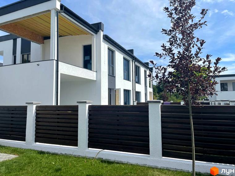 Котеджне містечко КМ Перлина Процева. Зовнішній вигляд білосніжних будинків з темним дахом та парканом з горизонтальних дерев'яних планок.