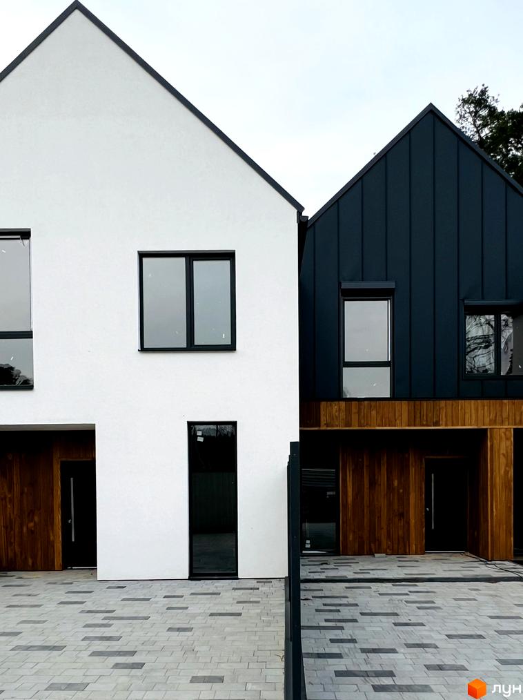 Котеджне містечко Toscana House 2. Фасад будинку виконаний у білому та темно-синьому кольорах з дерев'яними вставками. Перед будинком розташована бруківка.