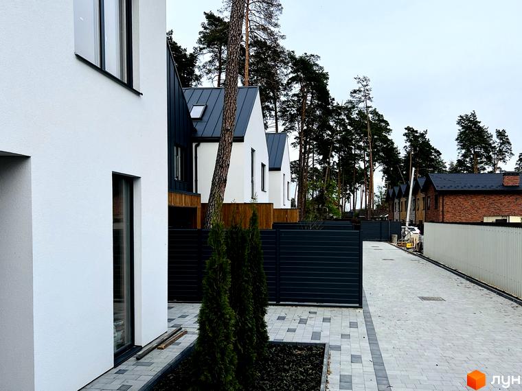 Котеджне містечко Toscana House 2: білі фасади будинків з темними дахами та прибудинкова територія з бруківкою та зеленими насадженнями.