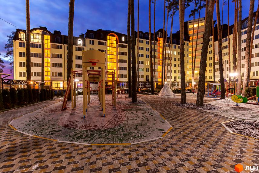 Житловий комплекс Ірпінські Липки. Багатоповерховий будинок жовтого кольору з великими вікнами, дитячий майданчик та зони відпочинку на прибудинковій території.