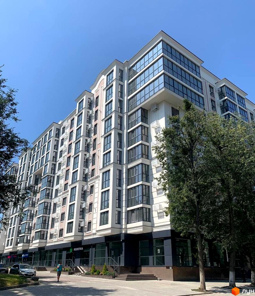 Зовнішній вигляд житлового комплексу GREAT HOUSE з великою кількістю вікон та балконів. Навколо будівлі розташовані дерева та тротуар.