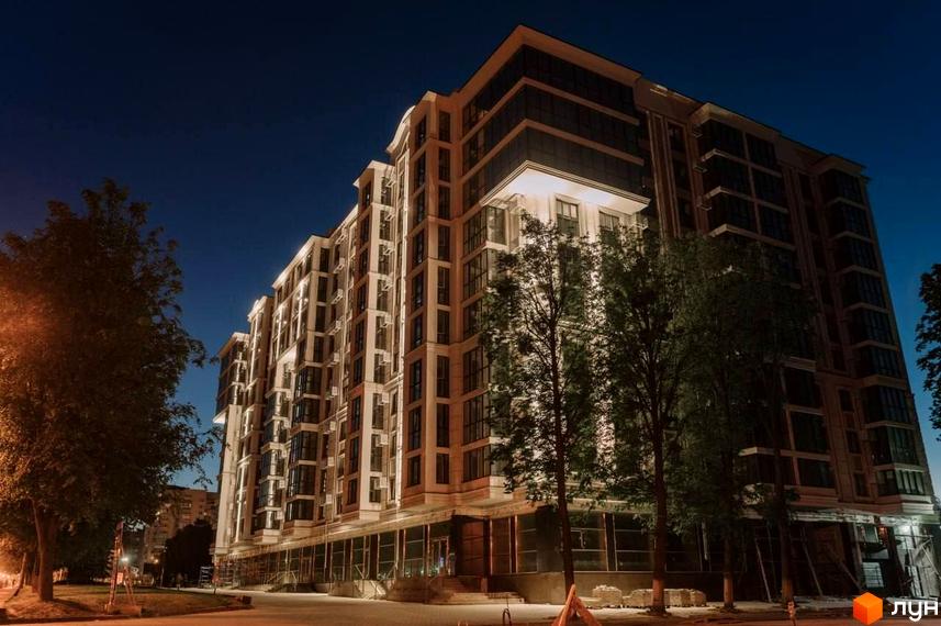 Житловий комплекс GREAT HOUSE з підсвіченим фасадом та вікнами, оточений деревами вночі. Зовнішній вигляд новобудови з багатою архітектурою.