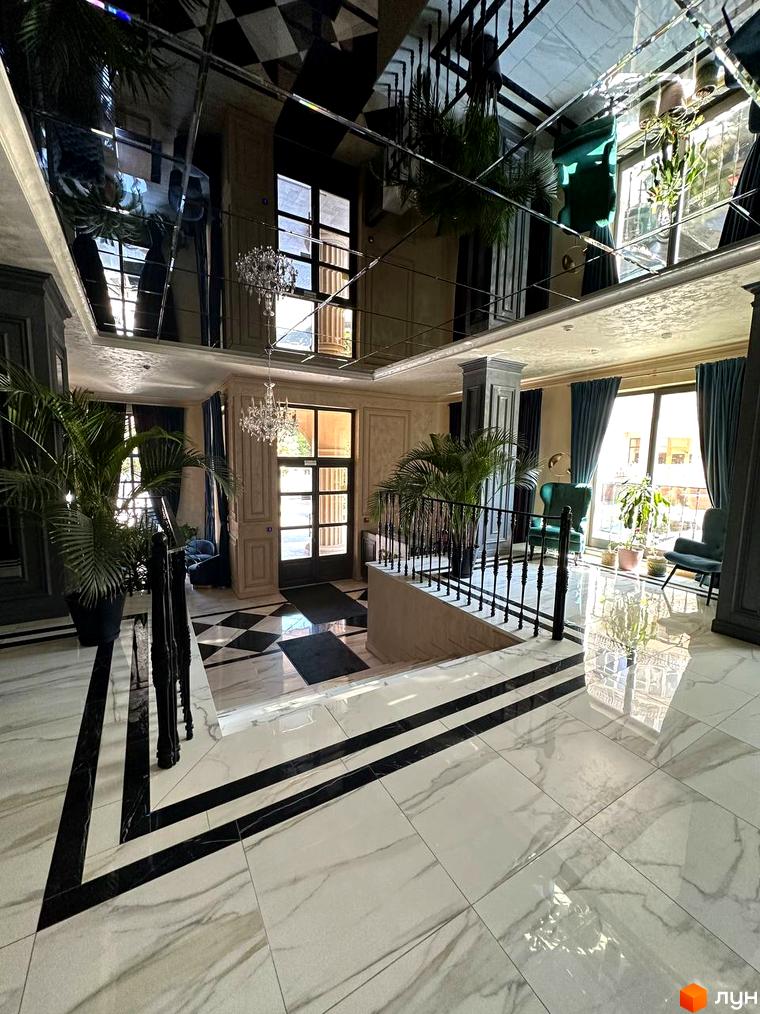 Клубний будинок Graf. Елегантний інтер'єр холу з мармуровою підлогою, великими вікнами та зеленню. Сучасний дизайн та розкішне оздоблення створюють затишну атмосферу.