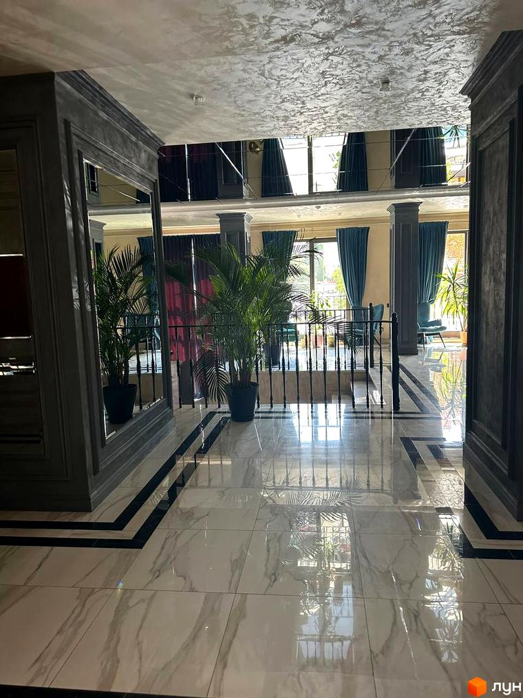 Клубний будинок Graf. Інтер'єр холу з мармуровою підлогою, великими дзеркалами та рослинами. Балкон з видом на місто.
