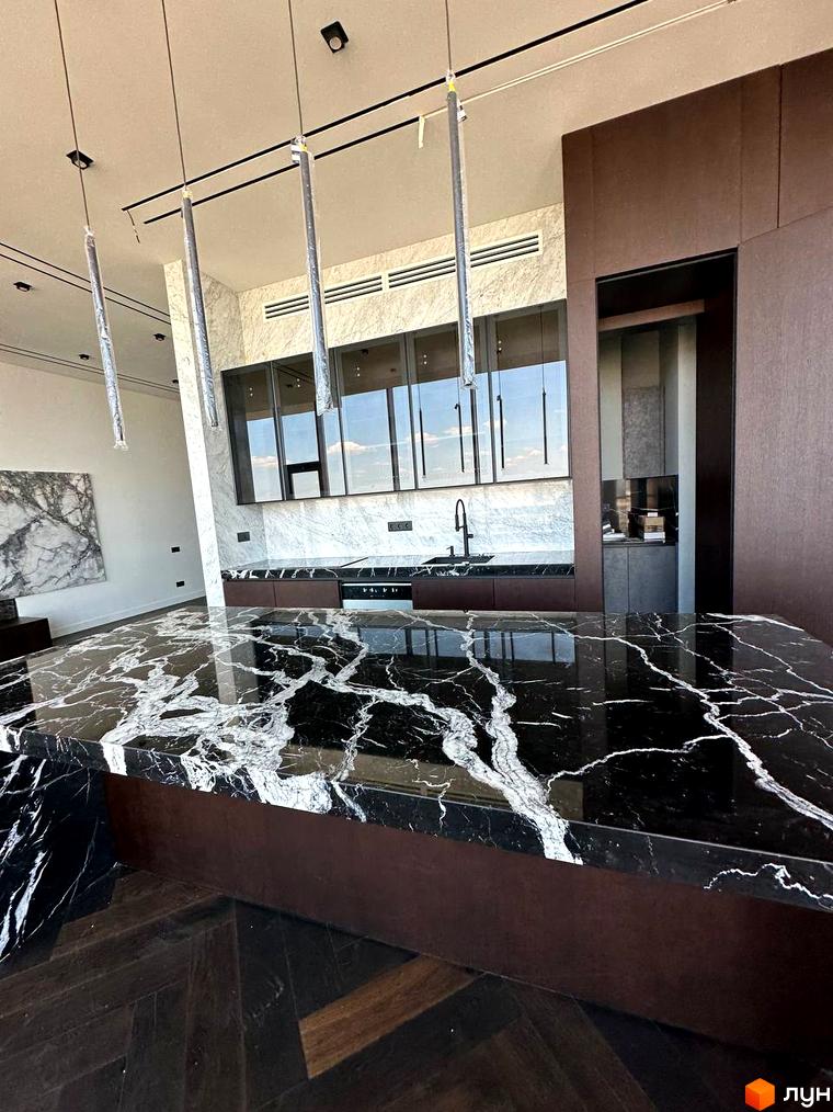 Клубний будинок Graf: інтер'єр кухні з мармуровою стільницею та темними фасадами. Сучасний дизайн інтер'єру кухні в новобудові.