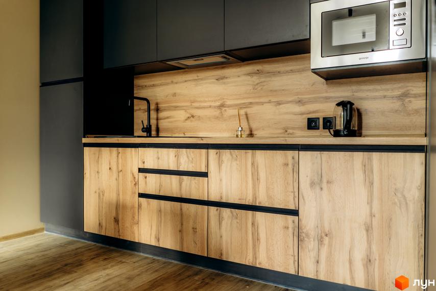 Сучасна кухня з дерев'яними фасадами та чорними елементами в комплексі КМ Gutenberg. Вбудована техніка та стильний дизайн.