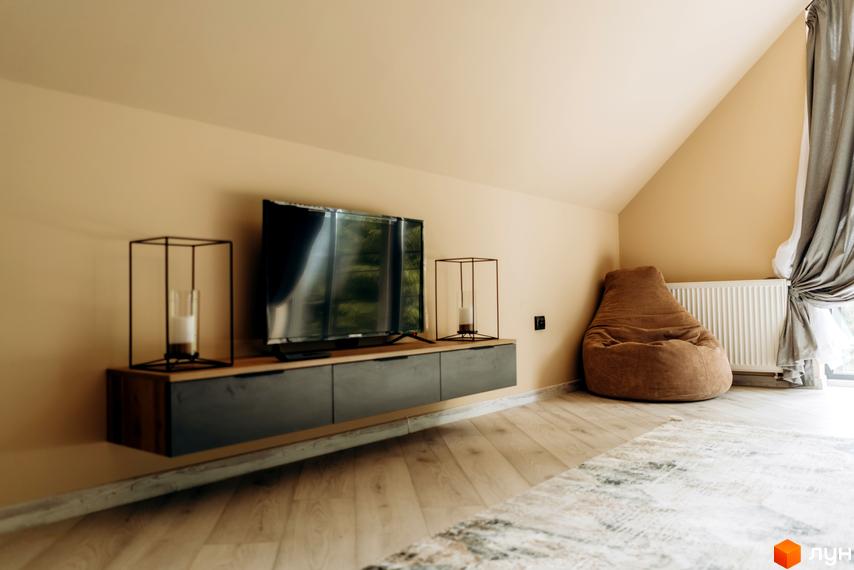 Вітальня з телевізором на стіні та кріслом-мішком в житловому комплексі КМ Gutenberg. Простора кімната з панорамними вікнами та сучасним дизайном.