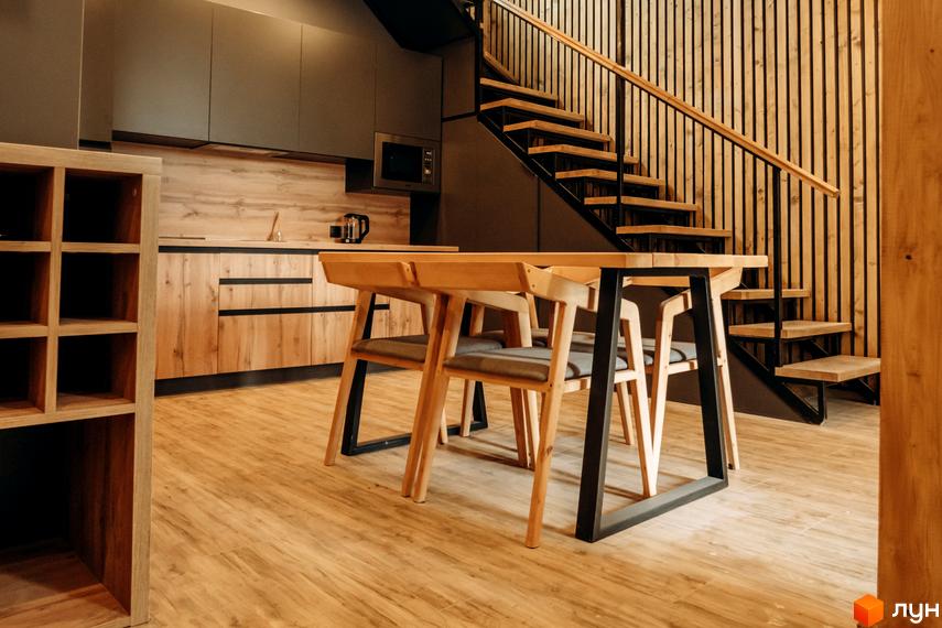 Інтер'єр кухні та їдальні в житловому комплексі КМ Gutenberg з дерев'яними елементами та сходами на другий поверх.