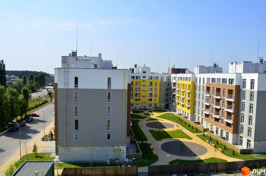 Житловий комплекс Столичний. Багатоповерхові будинки з сірими, білими та жовтими фасадами, балконами та прибудинковою територією з зеленими зонами та доріжками.