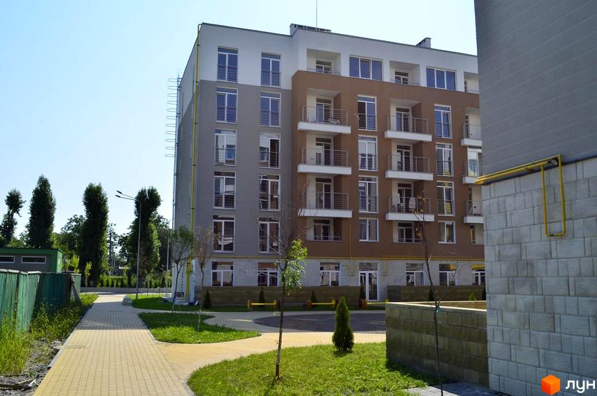 Житловий комплекс Столичний: багатоповерховий будинок з балконами та вікнами, прибудинкова територія з доріжками та зеленими насадженнями.