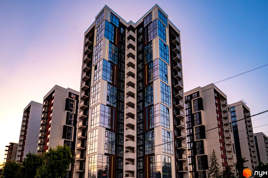 Житловий район Manhattan - сучасна архітектура з панорамними вікнами та балконами. Навколо новобудови зелені насадження та дерева.