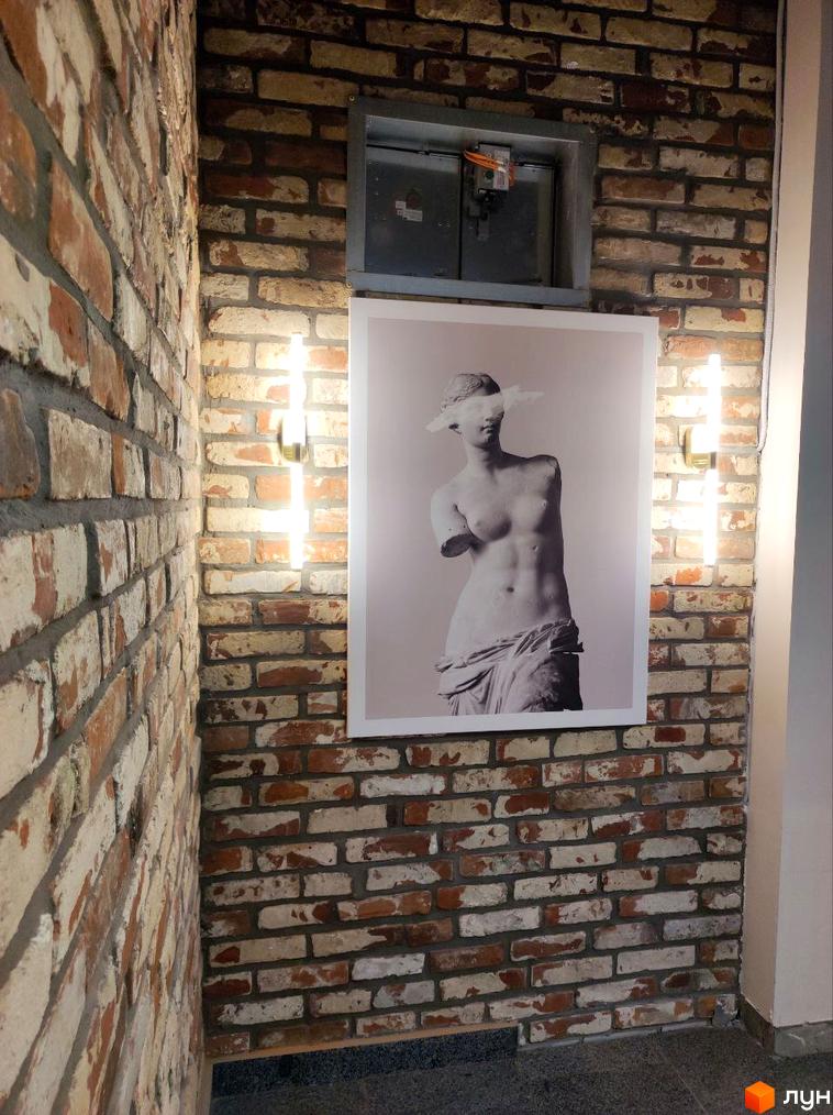 Житловий комплекс Loft White. Фотографія фасаду будинку з цегляною кладкою та арт-об'єктом.