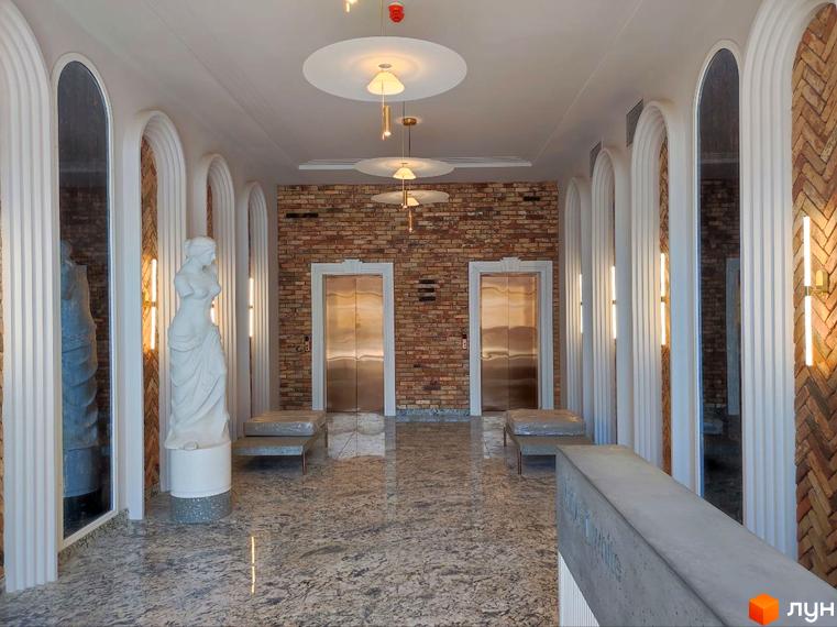 Вхідна група Житлового комплексу Loft White: інтер'єр холу з цегляною стіною, ліфтами та декоративними елементами.