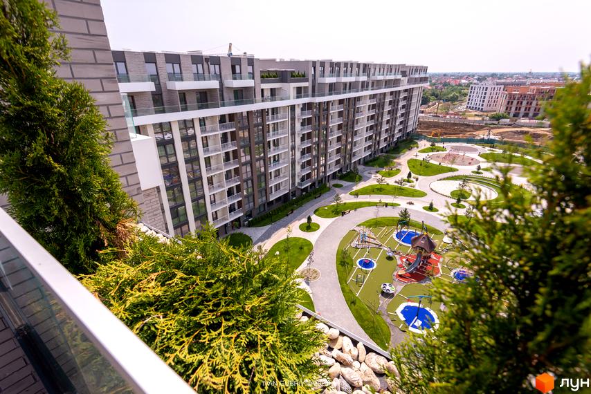 Вид на багатоповерховий житловий комплекс PARK LAND з балкона. На території комплексу розташовані дитячі майданчики та зелені зони.