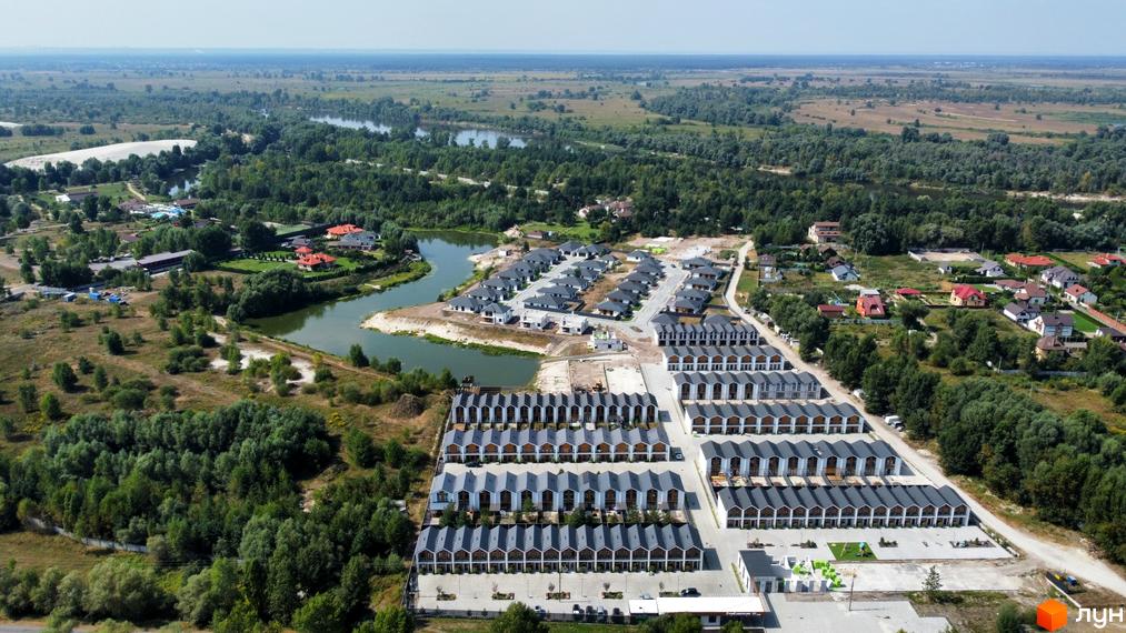 Панорамне фото Котеджного містечка Prydesennya Eco Village з будинками та прилеглою територією. Вид на річку та зелені насадження.