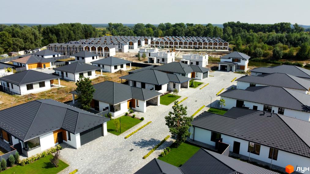 Фото Котеджного містечка Prydesennya Eco Village. Одноповерхові будинки з сірими дахами та білими стінами, перед будинками зелені газони.