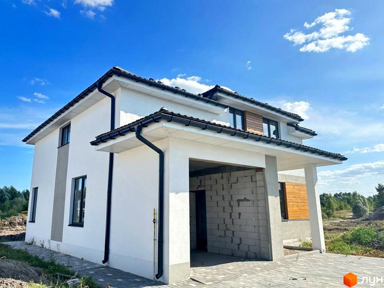 Зображення будинку в Котеджному містечку Prydesennya Eco Village. Двоповерховий будинок з білими стінами та чорним дахом на фоні блакитного неба.