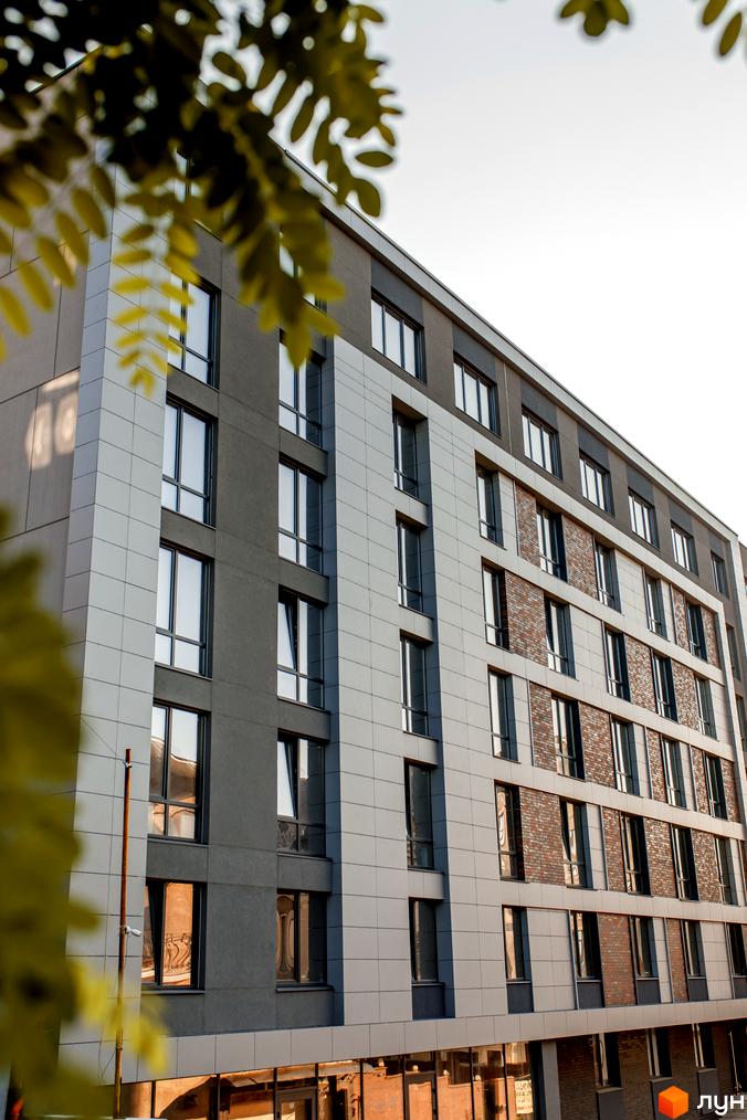 Фасад житлового комплексу Smart Concept з панорамними вікнами та комбінованою обробкою стін. Будинок має багатоповерхову структуру з чіткими геометричними формами.