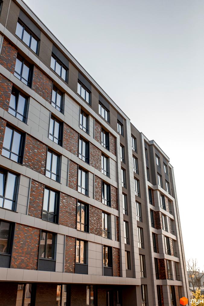 Фасад житлового комплексу Smart Concept з цегляними та світлими панельними вставками, великими вікнами. Сучасна архітектура новобудови.