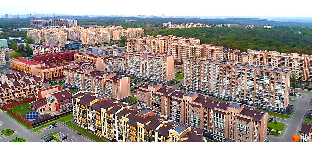 Житловий комплекс Кришталеві джерела: багатоповерхові будинки світло-бежевого кольору з коричневими дахами, зелені зони та паркувальні місця.