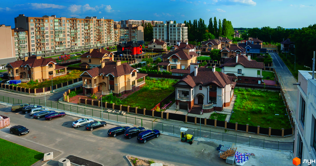 Житловий комплекс Кришталеві джерела. Сучасні будинки з коричневими дахами та світлими фасадами. На території комплексу є доглянуті газони та паркувальні місця.