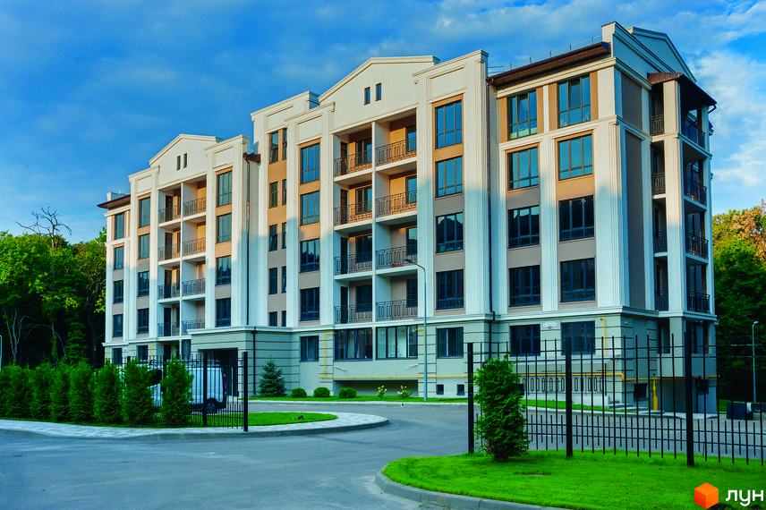 Фасад житлового комплексу Кришталеві джерела з балконами та великими вікнами. Прибудинкова територія з зеленими насадженнями та дорогою.