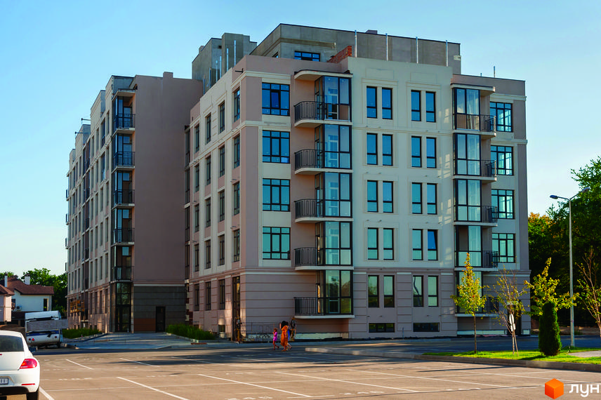 Житловий комплекс Кришталеві джерела: багатоповерховий будинок з балконами та великими вікнами. Прибудинкова територія з парковкою та зеленими насадженнями.